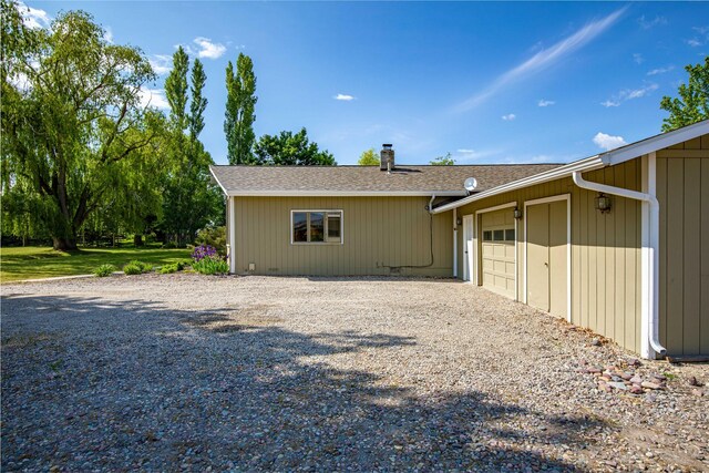 4291 Williams Ln, Stevensville, MT 59870 - view of home's exterior with gravel driveway, a garage, a chimney, and a shingled roof