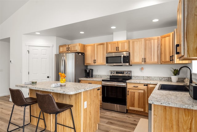 522 Pheasant Ln, Kalispell, MT 59901 - kitchen with appliances with stainless steel finishes, light wood-style flooring, light countertops, a kitchen bar, and a center island
