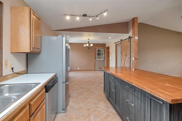 8340 Green Meadow Dr, Helena, MT 59602 - kitchen with vaulted ceiling, stainless steel dishwasher, a barn door, a chandelier, and light tile patterned flooring