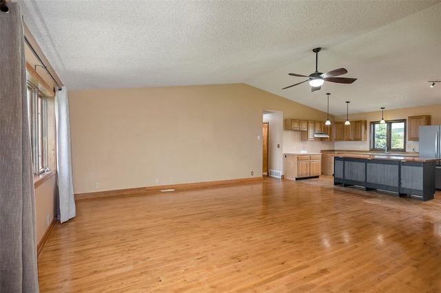 8340 Green Meadow Dr, Helena, MT 59602 - unfurnished living room with light wood-type flooring, a ceiling fan, lofted ceiling, and a textured ceiling