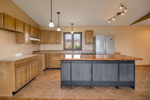 8340 Green Meadow Dr, Helena, MT 59602 - kitchen featuring freestanding refrigerator, under cabinet range hood, lofted ceiling, a kitchen island, and a textured ceiling