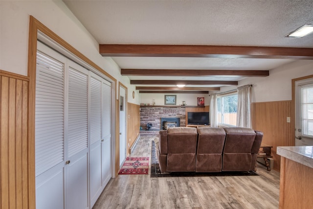 238 Hillcrest Dr, Hamilton, MT 59840 - living room featuring light wood-style floors, a wainscoted wall, beamed ceiling, wooden walls, and a textured ceiling