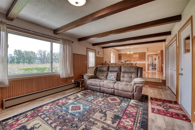 238 Hillcrest Dr, Hamilton, MT 59840 - living room featuring a baseboard radiator, wood finished floors, wooden walls, a chandelier, and a textured ceiling