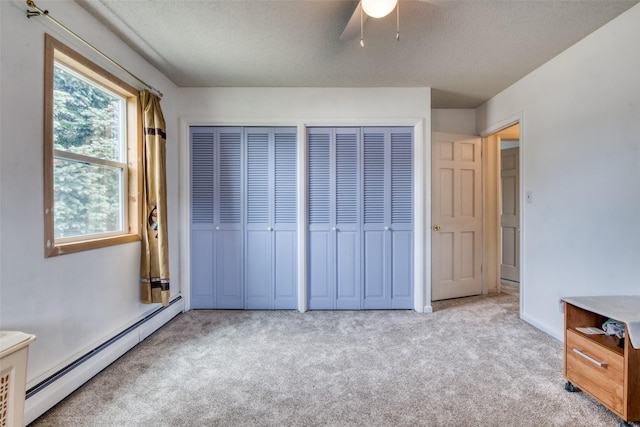 238 Hillcrest Dr, Hamilton, MT 59840 - unfurnished bedroom featuring a baseboard heating unit, carpet, two closets, a textured ceiling, and ceiling fan