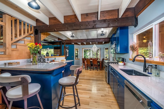 2075 Lion Mountain Loop Rd, Whitefish, MT 59937 - kitchen featuring blue cabinets, stainless steel appliances, beam ceiling, light wood finished floors, and a kitchen breakfast bar