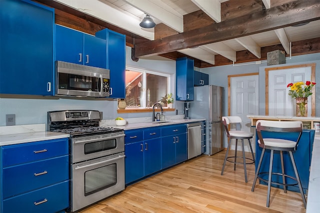 2075 Lion Mountain Loop Rd, Whitefish, MT 59937 - kitchen with stainless steel appliances, blue cabinets, beam ceiling, and light wood finished floors