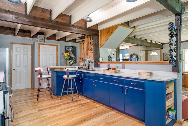 2075 Lion Mountain Loop Rd, Whitefish, MT 59937 - kitchen featuring blue cabinetry, beamed ceiling, stove, light wood-type flooring, and a peninsula