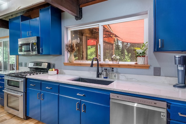 2075 Lion Mountain Loop Rd, Whitefish, MT 59937 - kitchen with blue cabinets, stainless steel appliances, light stone counters, and light wood-type flooring