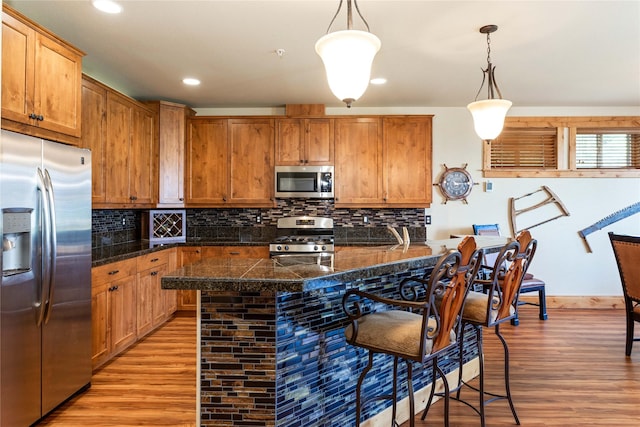 7175 US Highway 93 S Unit 4-102, Lakeside, MT 59922 - kitchen with stainless steel appliances, tile countertops, light wood-type flooring, a kitchen bar, and backsplash