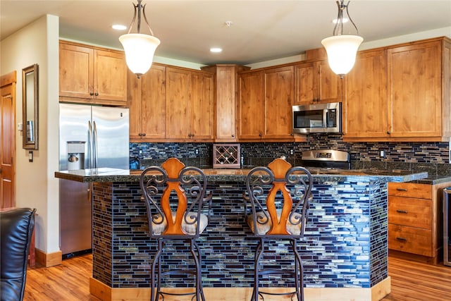 7175 US Highway 93 S Unit 4-102, Lakeside, MT 59922 - kitchen with appliances with stainless steel finishes, light wood-style flooring, pendant lighting, decorative backsplash, and recessed lighting