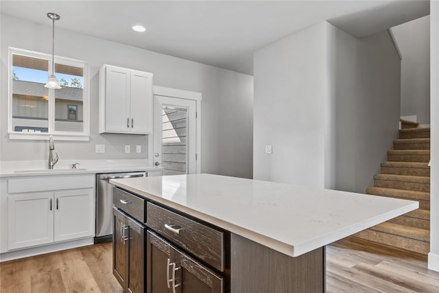534 Colorado Ave, Whitefish, MT 59937 - kitchen with stainless steel dishwasher, light countertops, white cabinets, light wood-style flooring, and hanging light fixtures