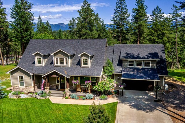 255 Windsor Ct, Bigfork, MT 59911 - view of front of property featuring a porch, driveway, an attached garage, a shingled roof, and stone siding