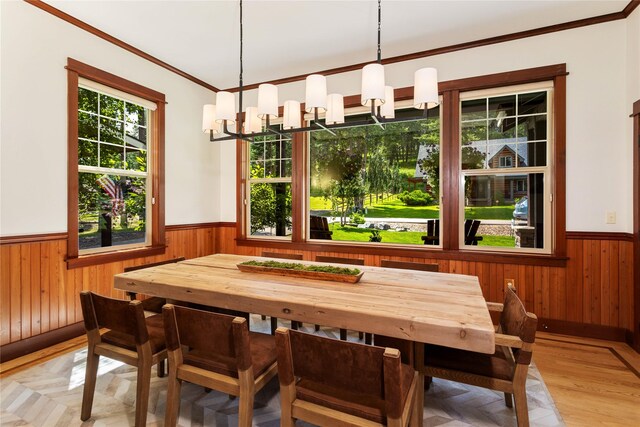 255 Windsor Ct, Bigfork, MT 59911 - dining area featuring wainscoting, wood walls, a chandelier, ornamental molding, and light wood-style flooring