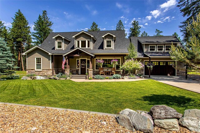 255 Windsor Ct, Bigfork, MT 59911 - back of house with covered porch, stone siding, a yard, and a shingled roof