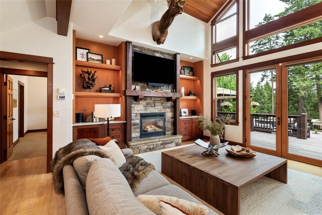 255 Windsor Ct, Bigfork, MT 59911 - living room featuring vaulted ceiling, light wood-style floors, a stone fireplace, and built in shelves