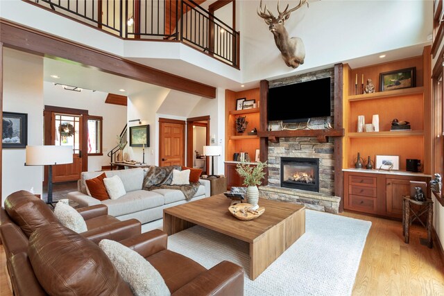 255 Windsor Ct, Bigfork, MT 59911 - living area with a stone fireplace, a high ceiling, light wood-style flooring, built in shelves, and stairs