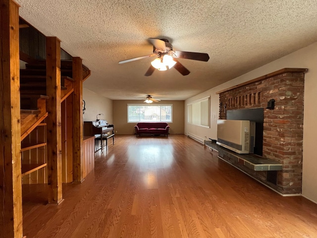 214 Church St, Thompson Falls, MT 59873 - living room with wood finished floors, a textured ceiling, ceiling fan, a baseboard heating unit, and stairs