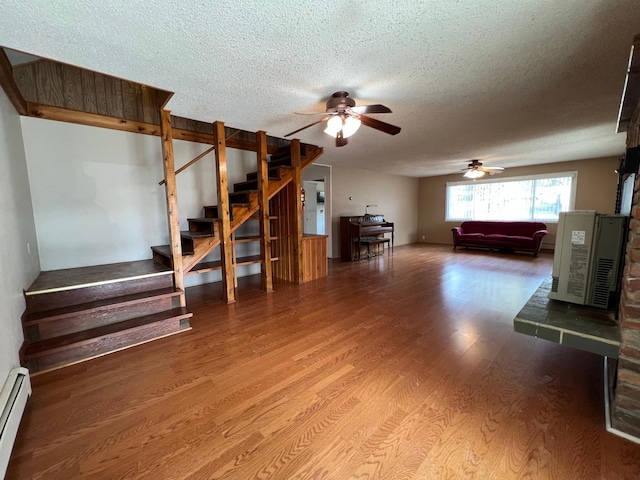 214 Church St, Thompson Falls, MT 59873 - living room with a ceiling fan, a textured ceiling, baseboard heating, stairway, and wood finished floors