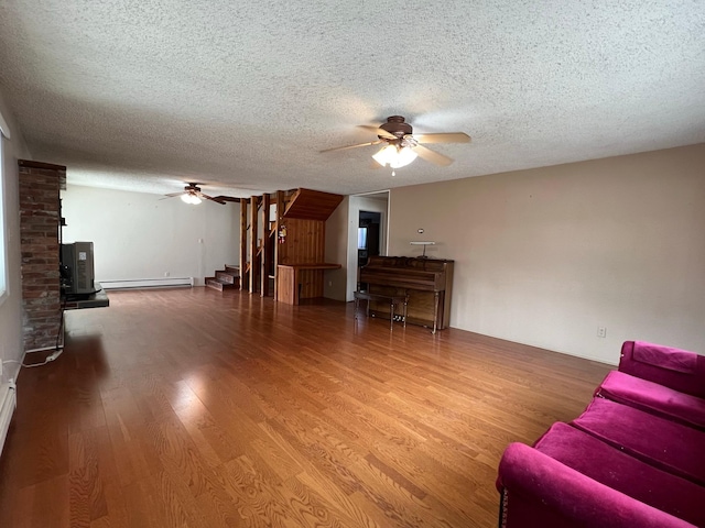 214 Church St, Thompson Falls, MT 59873 - living area featuring ceiling fan, a baseboard heating unit, a textured ceiling, wood finished floors, and a wood stove