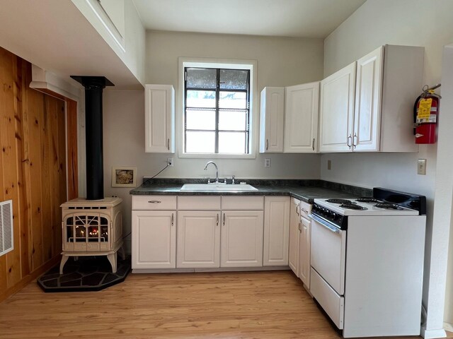 214 Church St, Thompson Falls, MT 59873 - kitchen featuring white stove, white cabinetry, dark countertops, and wood walls