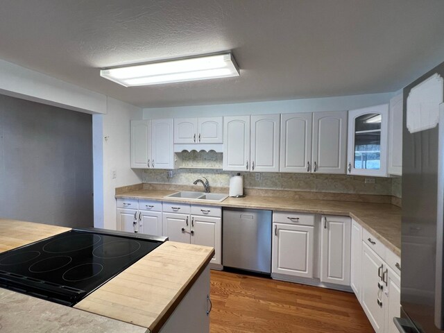 214 Church St, Thompson Falls, MT 59873 - kitchen with stainless steel dishwasher, range with electric stovetop, wood finished floors, white cabinets, and backsplash