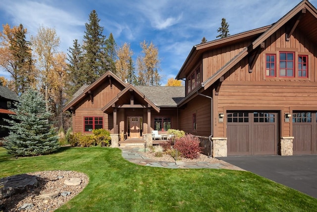 628 Nature Trl, Whitefish, MT 59937 - craftsman-style house with stone siding, a front lawn, asphalt driveway, an attached garage, and board and batten siding