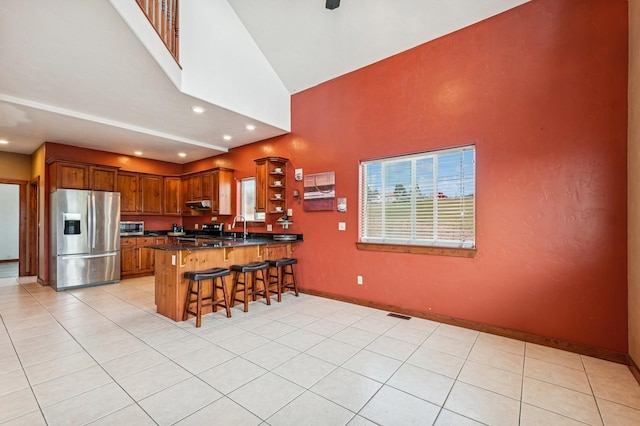 75 N Hill Rd, Kalispell, MT 59901 - kitchen with appliances with stainless steel finishes, high vaulted ceiling, a peninsula, under cabinet range hood, and a breakfast bar area