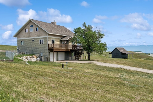 75 N Hill Rd, Kalispell, MT 59901 - back of property with driveway, a deck with mountain view, an attached garage, a chimney, and an outdoor structure