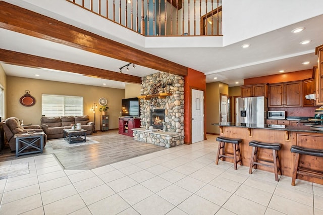 75 N Hill Rd, Kalispell, MT 59901 - living area featuring light tile patterned floors, a stone fireplace, recessed lighting, beamed ceiling, and a towering ceiling