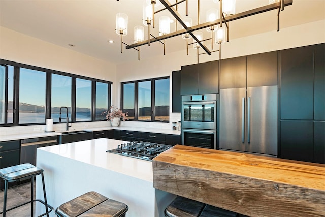 4722 Skalkaho Rd, Philipsburg, MT 59858 - kitchen with appliances with stainless steel finishes, pendant lighting, a kitchen bar, a chandelier, and dark cabinetry
