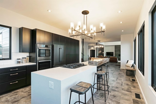 4722 Skalkaho Rd, Philipsburg, MT 59858 - kitchen with appliances with stainless steel finishes, dark cabinetry, a kitchen island, a kitchen bar, and recessed lighting