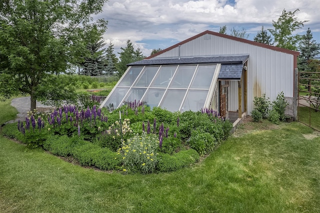 182 Moondance Trl, Bigfork, MT 59911 - view of property exterior with a shingled roof, a greenhouse, and an outdoor structure