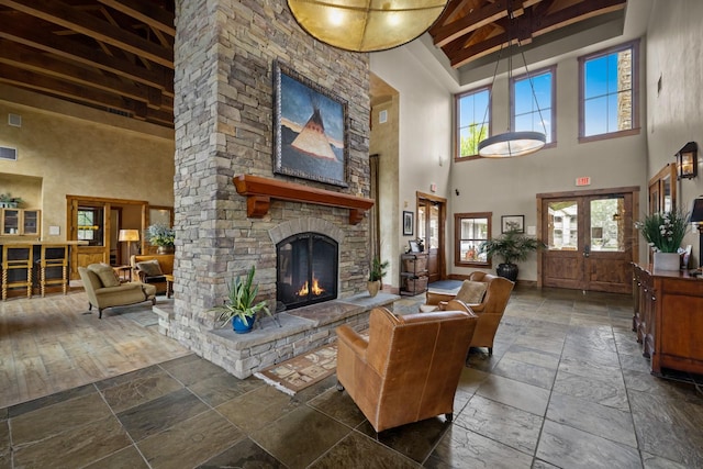 6203 Monterra Ave Unit H, Whitefish, MT 59937 - living area featuring a towering ceiling, stone tile floors, plenty of natural light, beam ceiling, and a stone fireplace