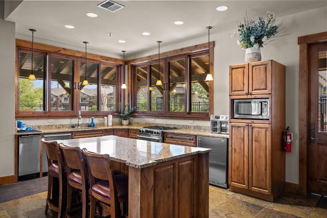 6203 Monterra Ave Unit H, Whitefish, MT 59937 - kitchen with appliances with stainless steel finishes, light stone counters, a center island, recessed lighting, and decorative light fixtures