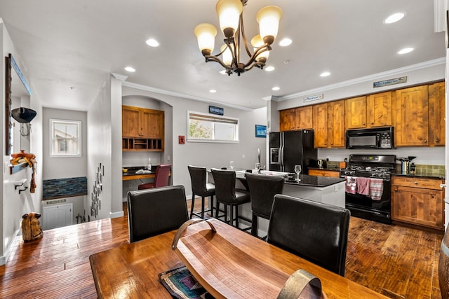 6203 Monterra Ave Unit H, Whitefish, MT 59937 - kitchen with black appliances, brown cabinets, dark countertops, crown molding, and dark wood-style floors