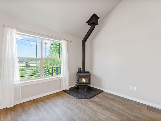 521 Evening Star Ln, Columbia Falls, MT 59912 - unfurnished living room featuring a wood stove, wood finished floors, and vaulted ceiling