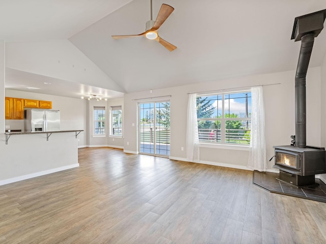 521 Evening Star Ln, Columbia Falls, MT 59912 - unfurnished living room featuring ceiling fan, a wood stove, light wood finished floors, and high vaulted ceiling