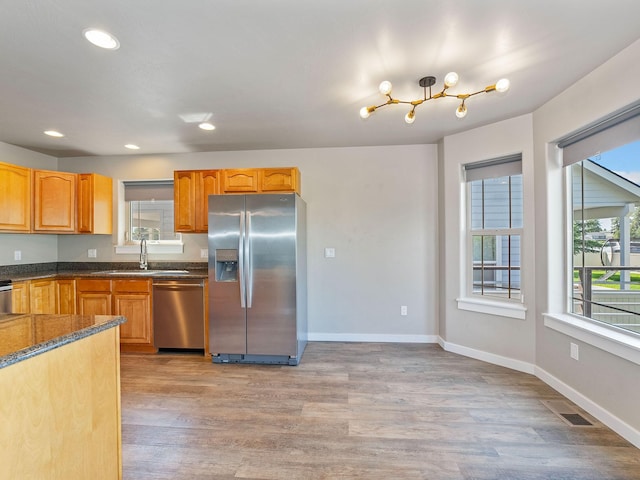521 Evening Star Ln, Columbia Falls, MT 59912 - kitchen featuring appliances with stainless steel finishes, light wood-style floors, recessed lighting, a chandelier, and dark stone counters