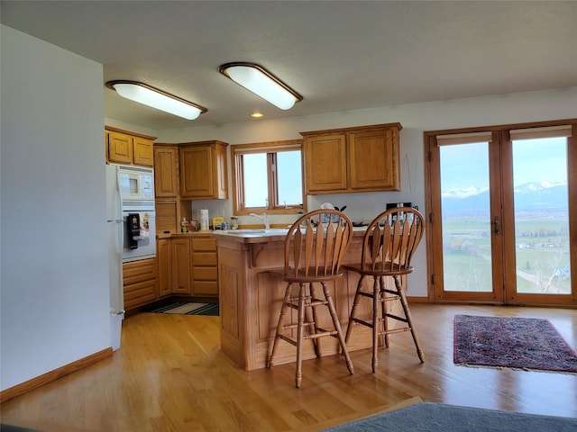 650 Hollibaugh Rd, Stevensville, MT 59870 - kitchen with a kitchen bar, light wood-style flooring, white microwave, and brown cabinets