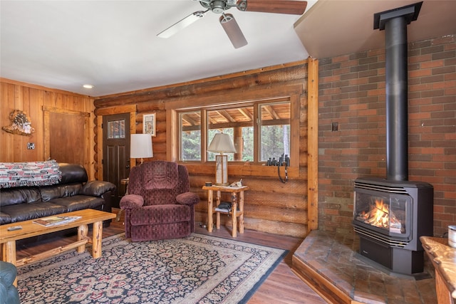 6343 Packer Creek Rd, Haugan, MT 59842 - living area featuring a wood stove, a ceiling fan, wood finished floors, and rustic walls