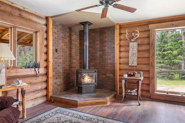 6343 Packer Creek Rd, Haugan, MT 59842 - living room with log walls, a wood stove, hardwood / wood-style floors, and a ceiling fan