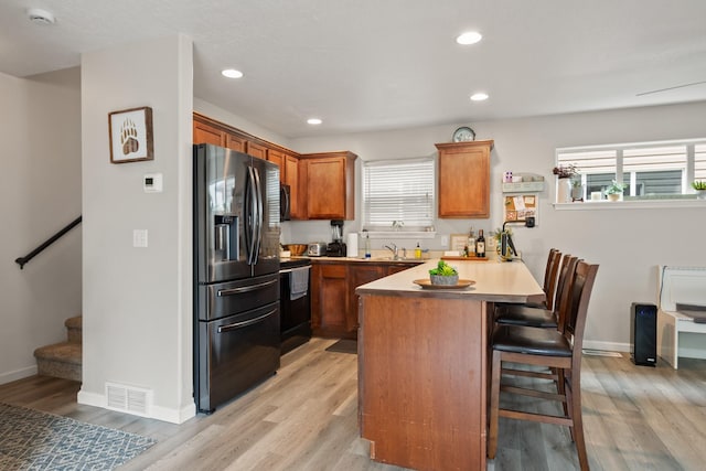 2331 W Sussex Ave, Missoula, MT 59801 - kitchen with stainless steel refrigerator with ice dispenser, a peninsula, electric range oven, a kitchen breakfast bar, and brown cabinetry