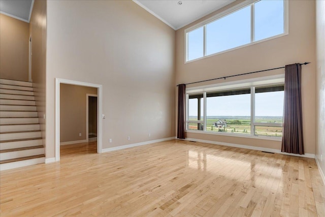 40 Butch Cassidy Loop, Great Falls, MT 59405 - unfurnished living room featuring ornamental molding, a towering ceiling, light wood-style flooring, plenty of natural light, and stairs