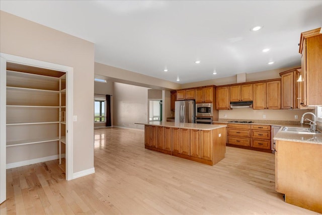 40 Butch Cassidy Loop, Great Falls, MT 59405 - kitchen featuring appliances with stainless steel finishes, under cabinet range hood, a kitchen island, light wood-style floors, and brown cabinetry