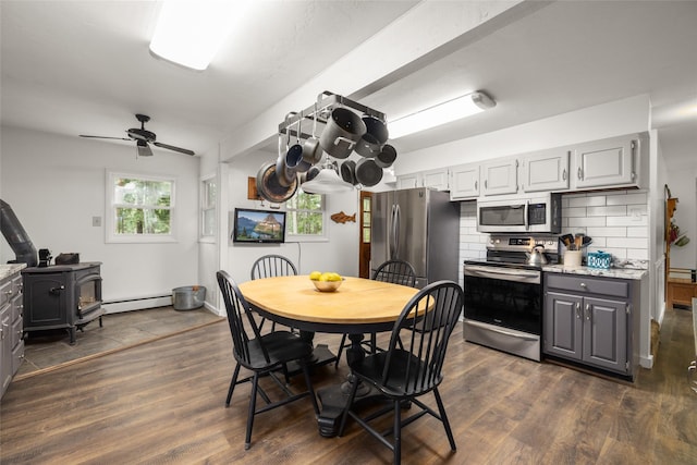155 Lake Peter Ct, Kalispell, MT 59901 - dining room with a baseboard radiator, a wood stove, dark wood finished floors, and a ceiling fan