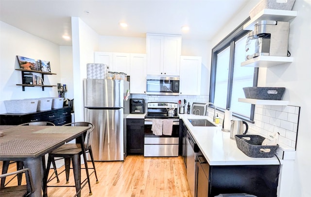 101 W Quartz St Unit 1A, Butte, MT 59701 - kitchen featuring appliances with stainless steel finishes, open shelves, white cabinets, light wood finished floors, and tasteful backsplash