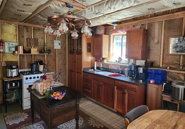 6570 Blossburg Rd, Canyon Creek, MT 59633 - kitchen featuring white gas stove, brown cabinetry, a chandelier, and dark countertops