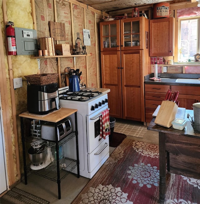 6570 Blossburg Rd, Canyon Creek, MT 59633 - kitchen featuring white gas range, brown cabinets, glass insert cabinets, and dark countertops