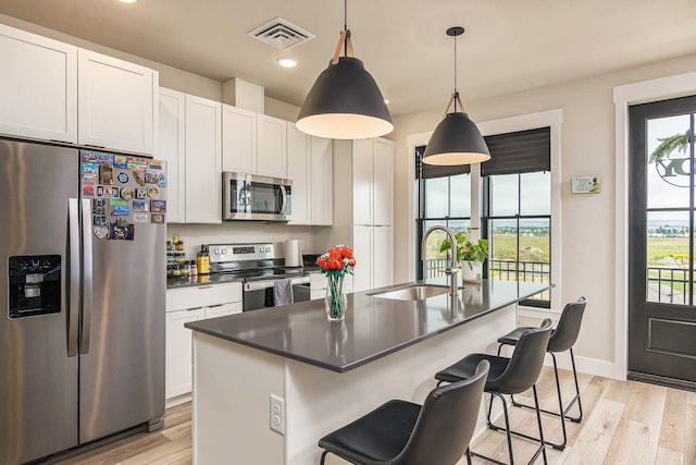 6170 Elysian Rd Unit 103-203, Billings, MT 59101 - kitchen featuring appliances with stainless steel finishes, light wood finished floors, white cabinets, recessed lighting, and a kitchen bar