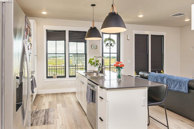 6170 Elysian Rd Unit 103-203, Billings, MT 59101 - kitchen featuring stainless steel appliances, white cabinets, light wood-type flooring, a kitchen island with sink, and pendant lighting